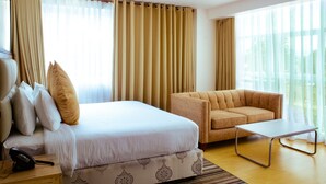 A hotel room with a bed, a sofa, a small table, and a telephone on a nightstand.