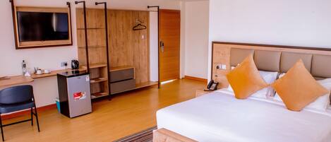 A hotel room with a bed, a desk, a chair, a wardrobe, and a television.