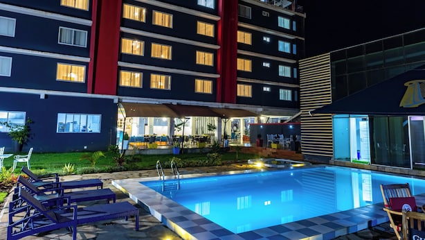 A hotel with a swimming pool, outdoor seating, and a well-lit building facade.