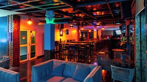 A modern bar area with seating, a staircase, and a decorative wall.