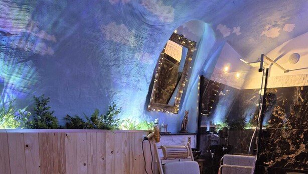An outdoor seating area with wooden furniture, a table with fruit, and string lights.