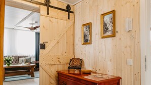 A wooden-paneled room with a large wooden door, a dresser, and two framed pictures on the wall.