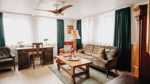 A cozy living room with a wooden coffee table, a sofa, a chair, and a desk.