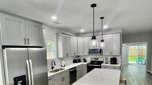 A modern kitchen with stainless steel appliances, a central island, and pendant lighting.