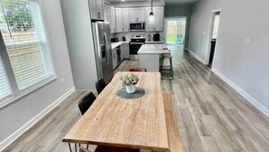 A modern kitchen with a dining area, wooden flooring, and a view of the outdoors.