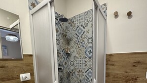 Une salle de bain moderne avec une douche, un lavabo et un mur en bois.
