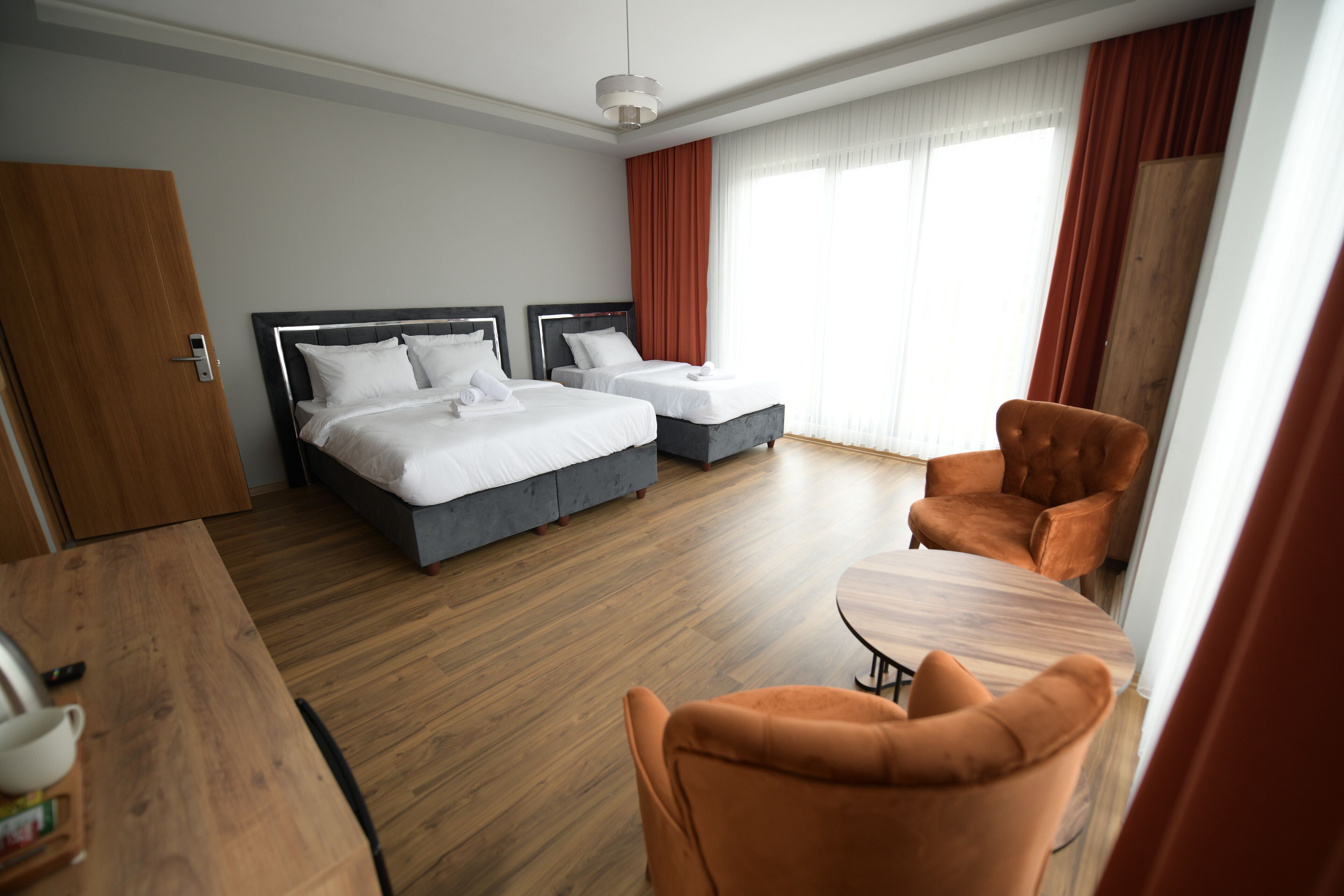 Una habitación de hotel con dos camas, suelo de madera, una mesa de comedor y una silla.