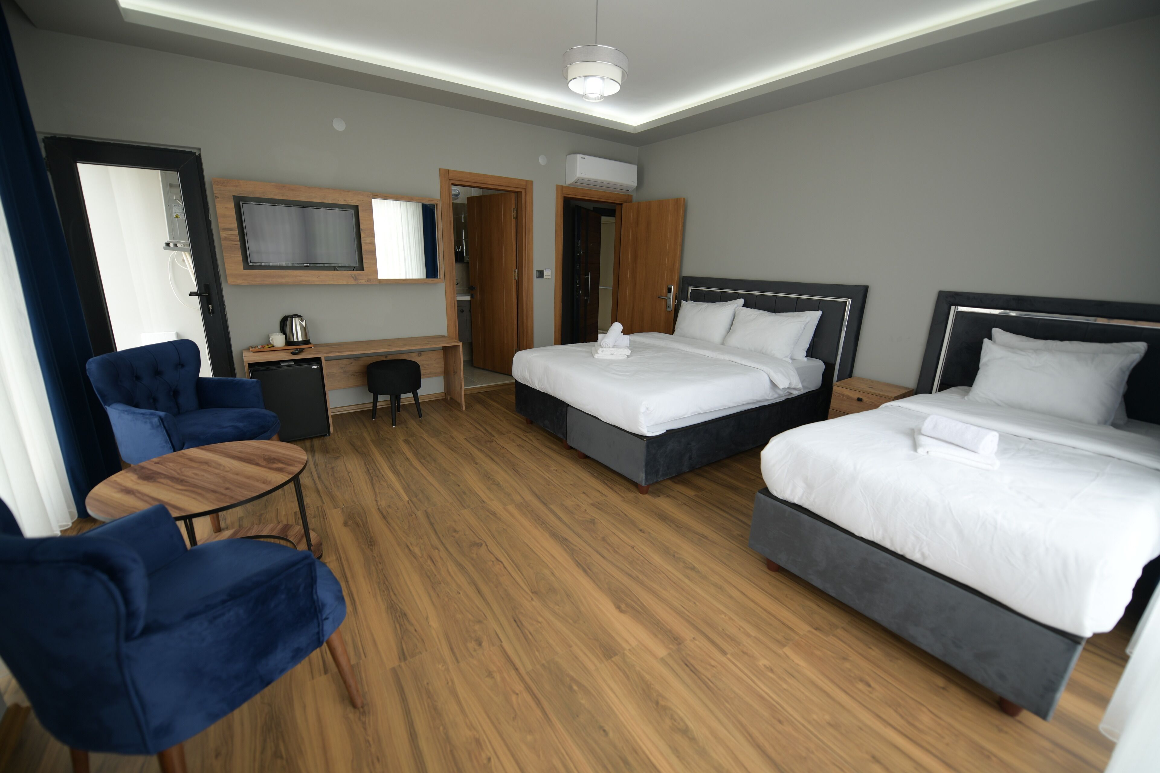 A hotel room with two beds, a desk, a chair, and a television.