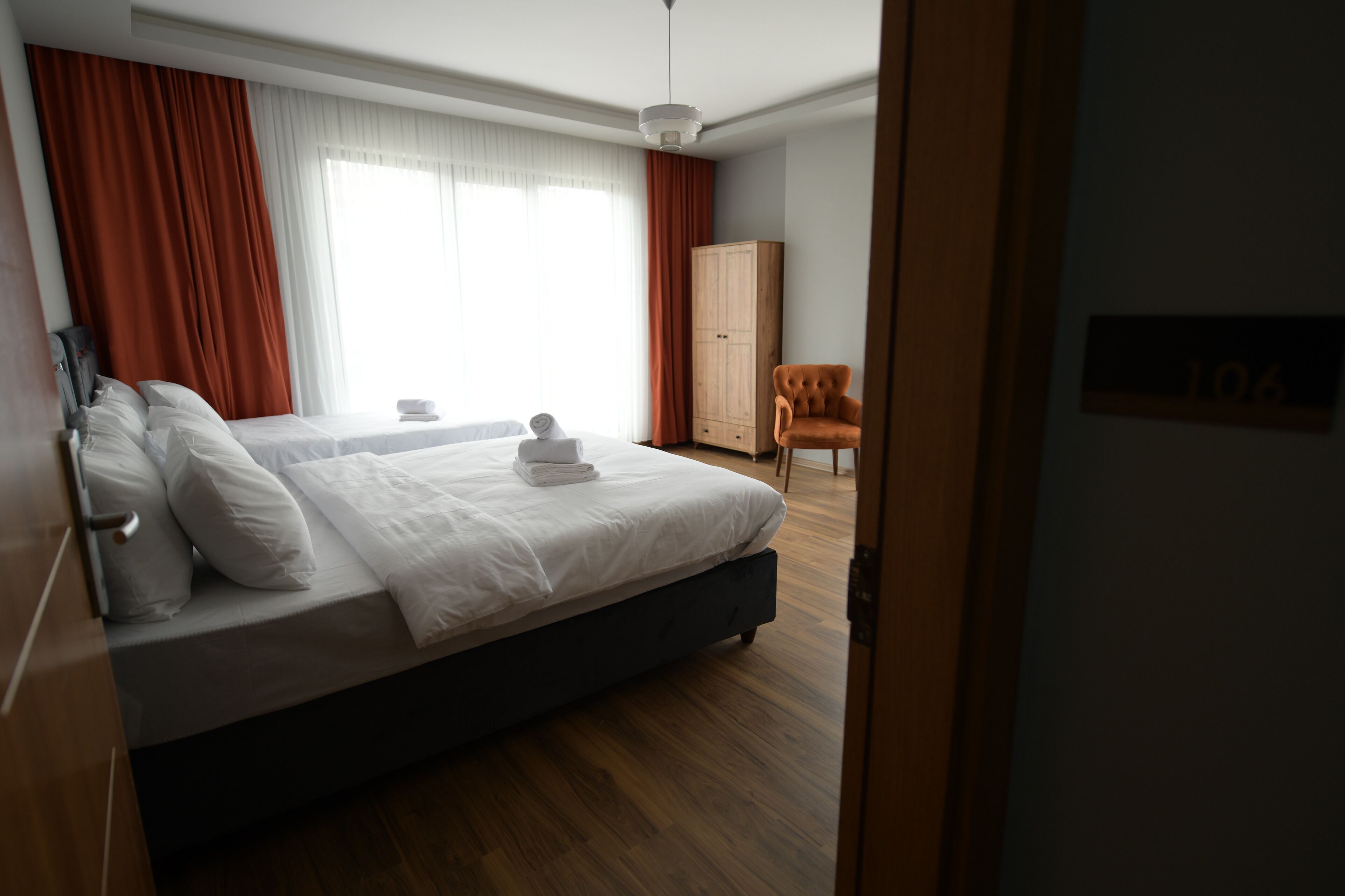 A modern hotel room with a large bed, a wardrobe, and a seating area.