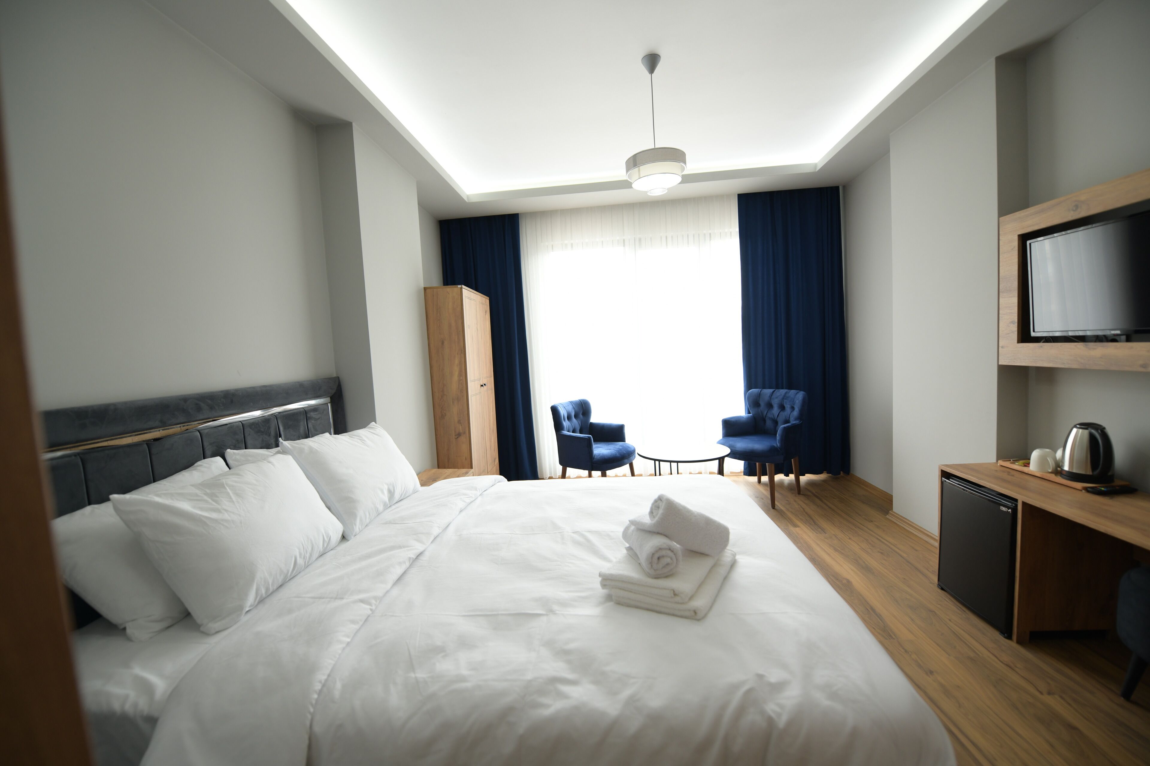 Una habitación de hotel con una cama grande, un escritorio con televisor y dos sillas.