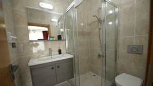 Une salle de bain moderne avec une douche à parois de verre, un lavabo avec un miroir au-dessus et des toilettes.