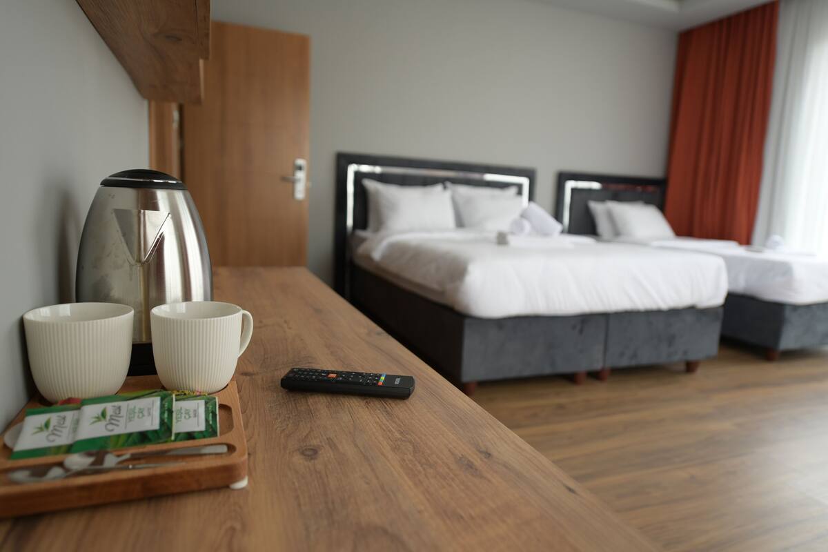 Ein Hotelzimmer mit einem Holztisch, zwei weißen Tassen, einer Fernbedienung und einem Tablett mit Teebeuteln.