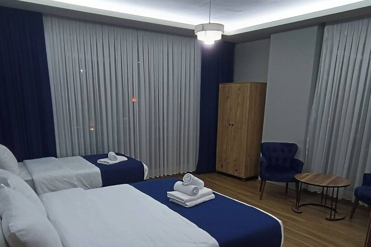 Ein Hotelzimmer mit zwei Betten, einem Holzschrank, einem kleinen Tisch und einem blauen Sessel.