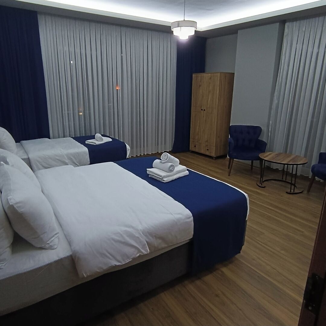 Una habitación de hotel con dos camas, un armario de madera, una mesita pequeña y un sillón azul.