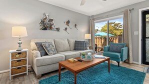 A living room with a sofa, a coffee table, a blue rug, wicker storage, and wall art. - Updated 2BR/2BA Condo in North Ocean City, MD | Indoor + Outdoor Pools | 2 Blocks to Beach | Walk to Food Lion & Restaurants | Sleeps 6 (Ocean City)