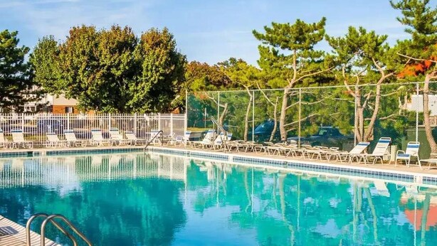 A swimming pool with lounge chairs and a wooden deck. - Updated 2BR/2BA Condo in North Ocean City, MD | Indoor + Outdoor Pools | 2 Blocks to Beach | Walk to Food Lion & Restaurants | Sleeps 6 (Ocean City)