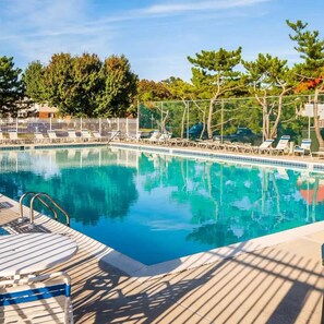 Ein Schwimmbecken mit Liegestühlen und einer Holzterrasse.