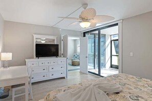 A bedroom with a bed, a dresser, a TV, and a ceiling fan.