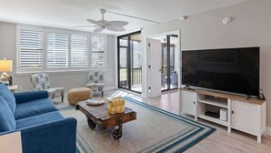 A living room with a sofa, a coffee table, a TV, and a ceiling fan.