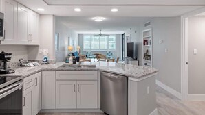A modern kitchen with white cabinets, a granite countertop, and a dishwasher.