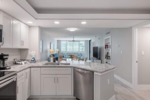 A modern kitchen with white cabinets, a granite countertop, and a dishwasher.