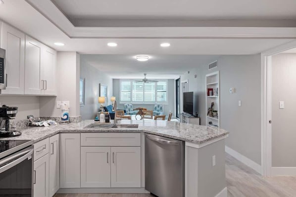 A modern kitchen with white cabinets, a granite countertop, and a dishwasher.
