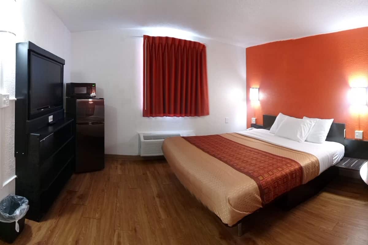 A hotel room with a bed, a TV, a small table, and a chair.
