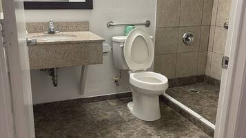 A bathroom with a toilet, sink, and shower area.