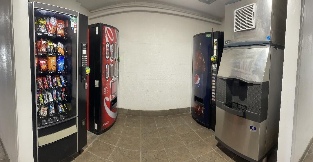 A corner with vending machines and a refrigerator.