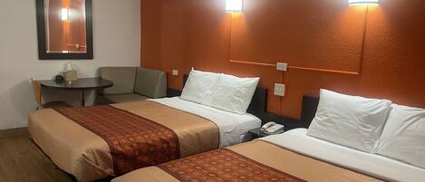 Quarto de hotel com duas camas, uma mesa pequena, uma cadeira e telefone fixado na parede.