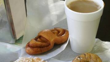 A table with a white cup of coffee, two pastries, and a box.