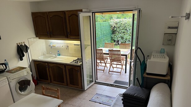 Une cuisine compacte équipée d’un lave-linge, d’un évier et d’un coin repas avec des chaises.