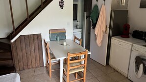 Une cuisine équipée d’une table à manger, de chaises, d’un lave-linge et d’un escalier.