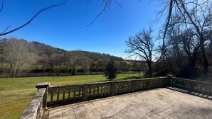A stone patio with a view of a grassy field and trees. - Private House (ADA Access) at Domaine de Puygiraud sur L'Anglin for 12-14 guests (Saint-Pierre-de-Maillé)