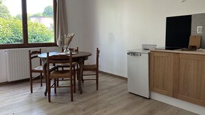 A kitchen with a wooden table and chairs, a white refrigerator, and a window with curtains. - Private House (ADA Access) at Domaine de Puygiraud sur L'Anglin for 12-14 guests (Saint-Pierre-de-Maillé)