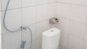A bathroom with a toilet, a wall-mounted bidet, and a showerhead. - THE VILLAGE INN Rua Beach  (Wanokaka)