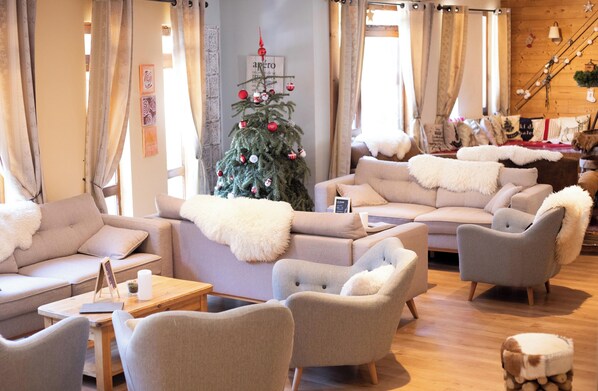 A cozy living room with a Christmas tree, comfortable sofas, and a wooden staircase.