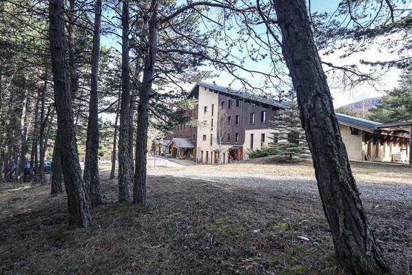 A building with a modern architectural style, surrounded by a forested area. - Domaine de L'Adoux (Montclar)