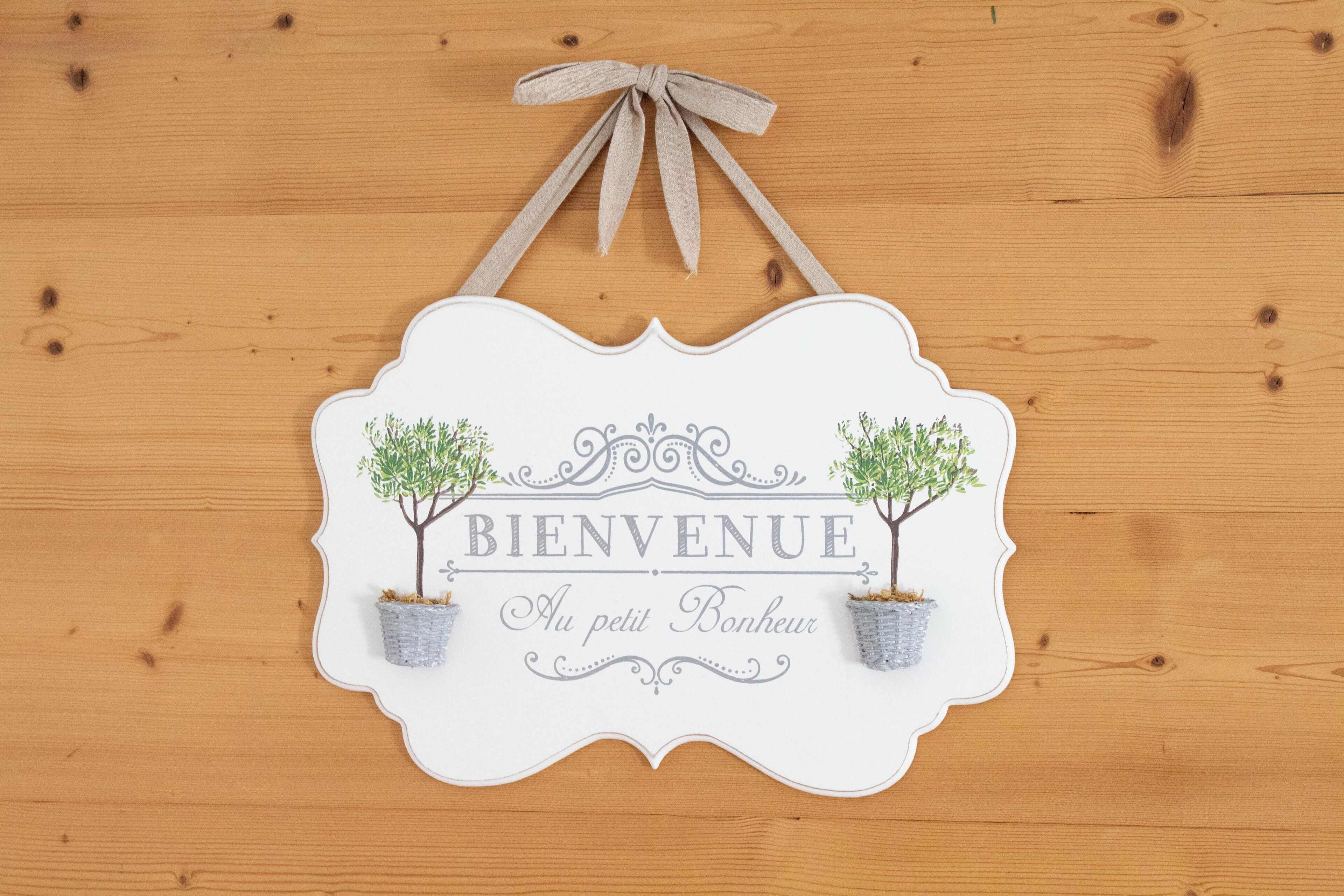 Un letrero de bienvenida con árboles decorativos y el texto 