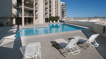Una piscina al aire libre, sillones reclinables de piscina