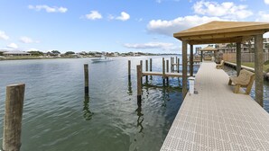 A wooden pier extending into calm water, with a covered seating area and a view of the distant shoreline. - Wind Drift South East 404 (Orange Beach)