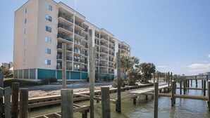 A multi-story hotel with balconies, located near a waterfront with wooden walkways. - Wind Drift South East 404 (Orange Beach)