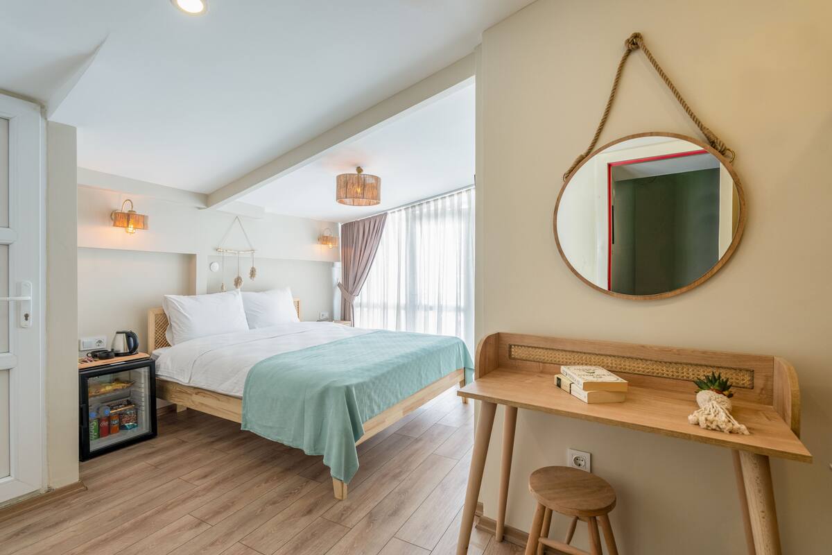 A bedroom with a bed, bedside table, and a small desk with a chair.