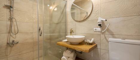 A modern bathroom with a glass shower enclosure, a round mirror, a wooden vanity with a sink, and a toilet.