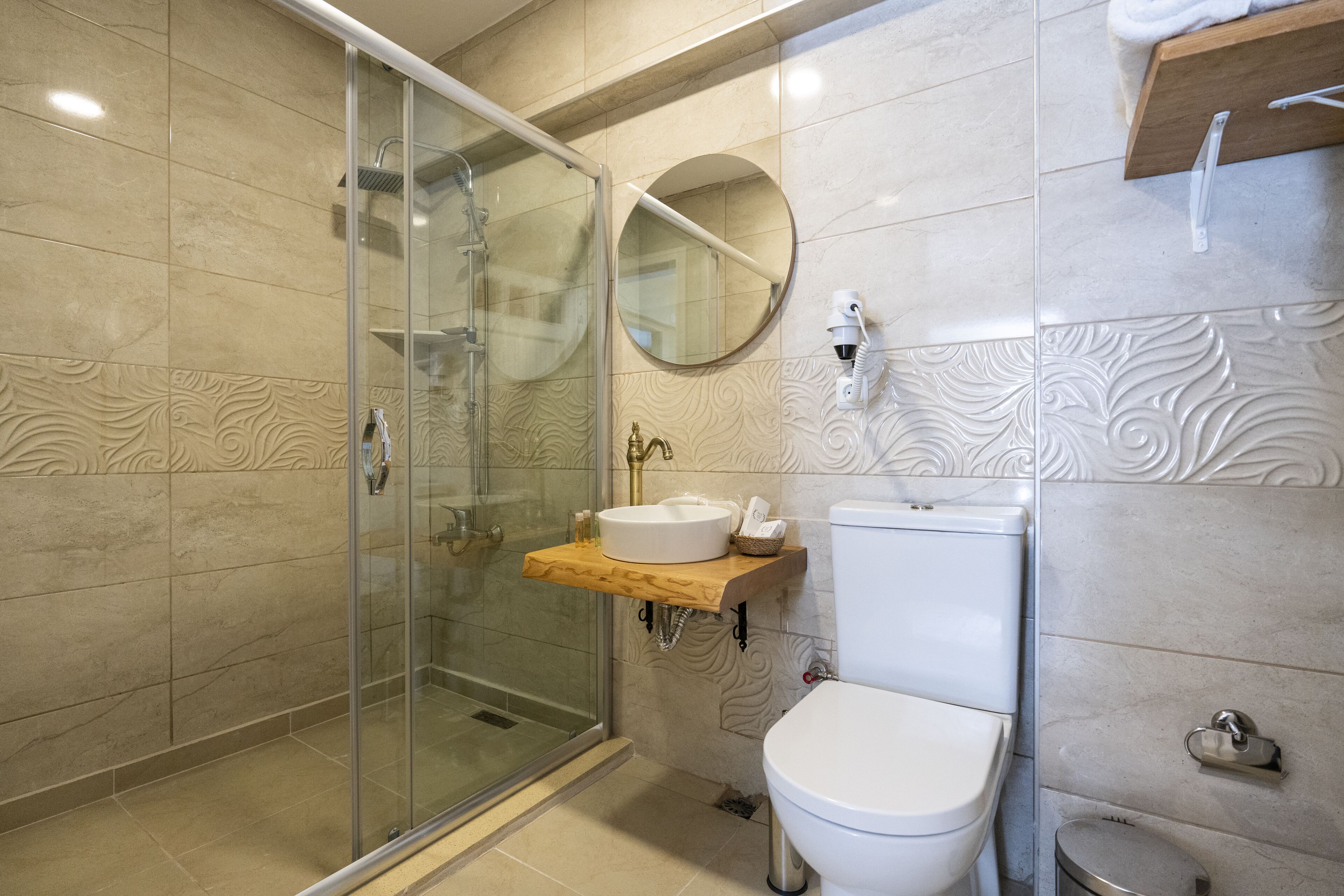A modern bathroom with a glass-enclosed shower, a wooden vanity with a sink, and a toilet.
