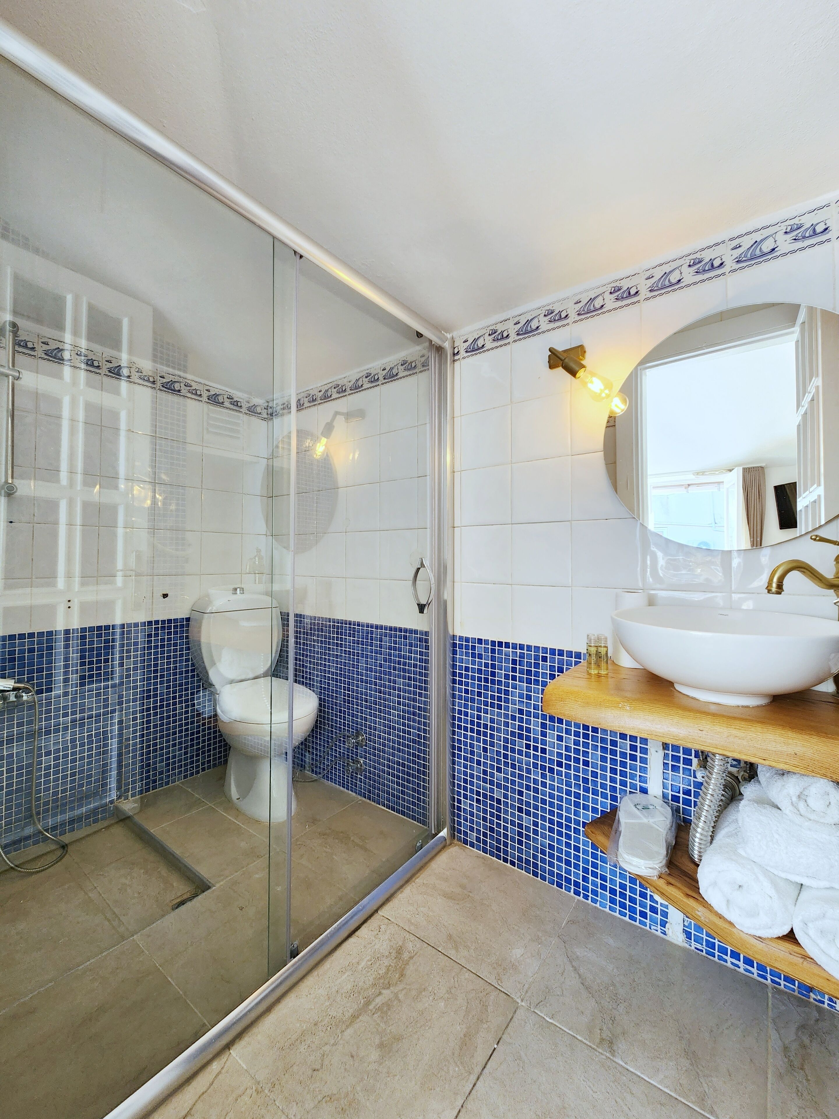 A bathroom with a glass-enclosed shower, a toilet, and a sink with a mirror.