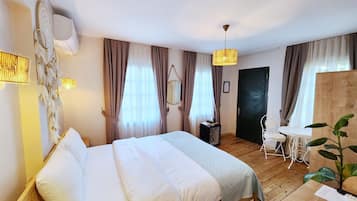 Een hotelkamer met een houten bed, een tafeltje, een stoel, een bureau en een potplant.