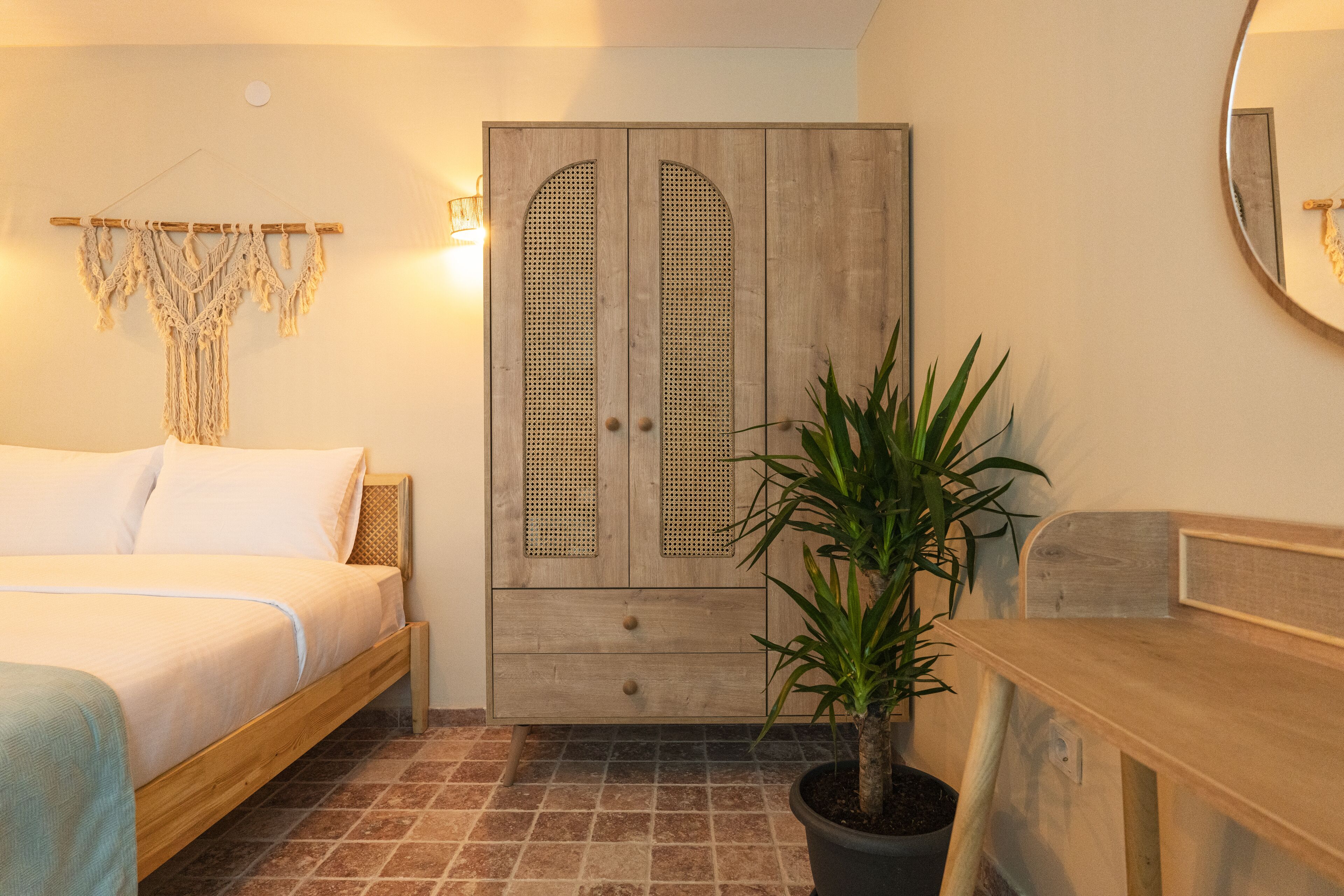 Une chambre à coucher avec un lit, une armoire en bois, une plante en pot et un miroir.