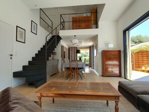 Uma sala de estar moderna com escada, área de jantar e vista para o exterior.