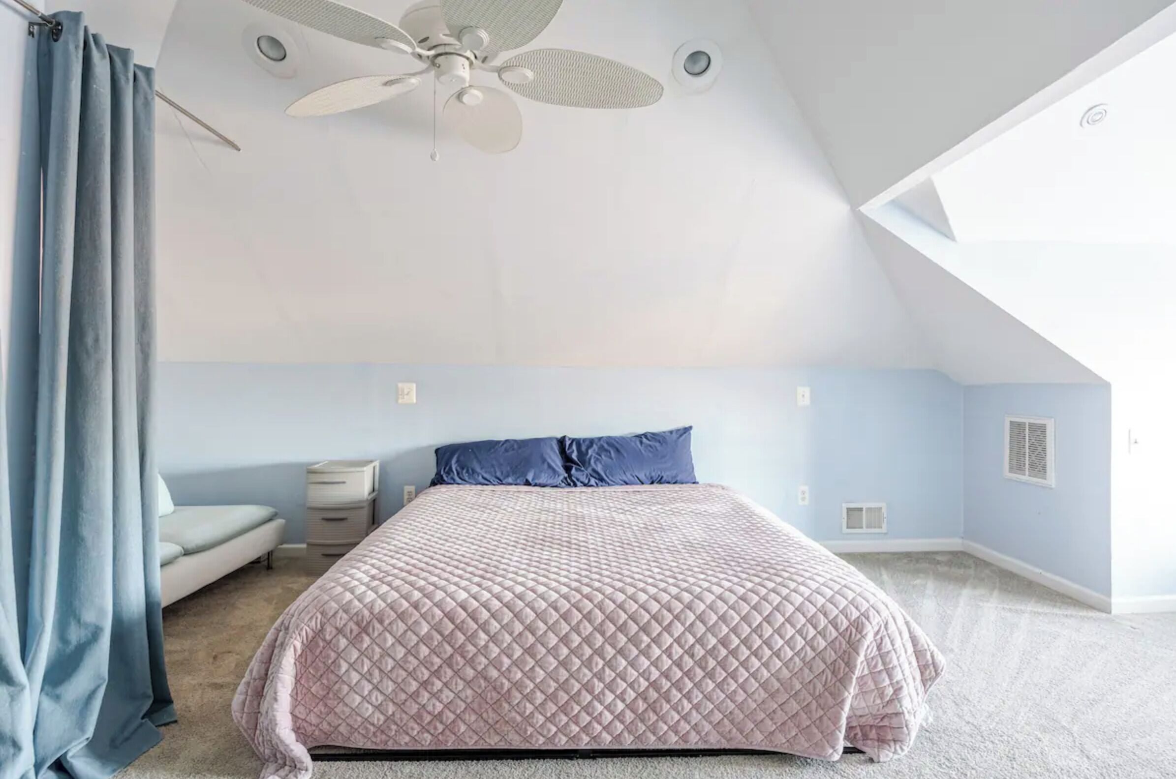 Ein Schlafzimmer mit Bett, Deckenventilator, Nachttisch und Fenster.